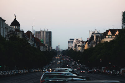 Vehicles on road amidst buildings in city against clear sky