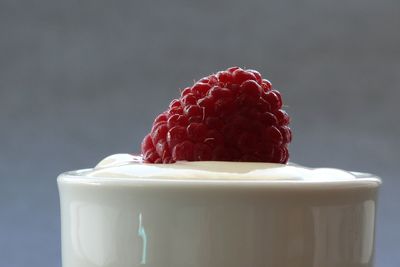Close-up of yogurt with raspberry against gray background