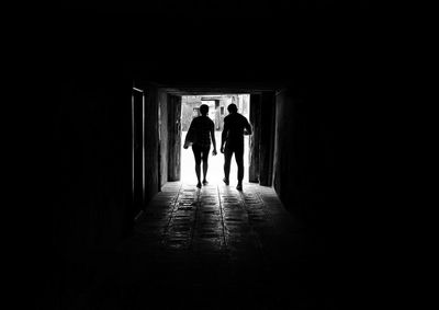 Silhouette people walking in tunnel