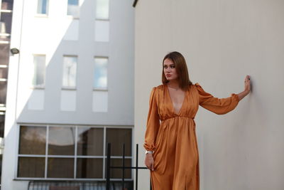 Young woman looking away while standing against wall