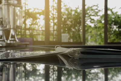 Close-up of menu on glass table with reflection at cafe