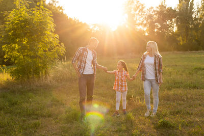 Happy family with a kite playing at sunset in the field