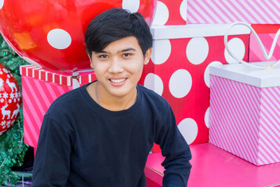 Portrait of young man sitting by gift boxes