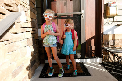 Two girls holding silly paper glasses on front porch