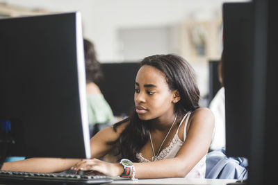 Confident girl using computer at desk in classroom