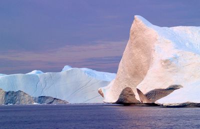 Lake and iceberg against sky on sunny day