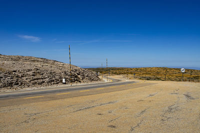 Road by building against clear blue sky