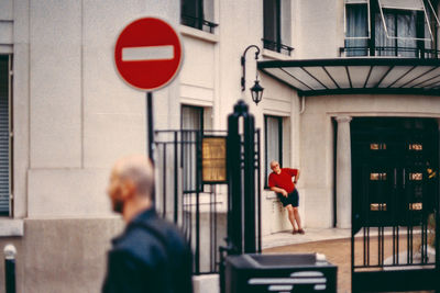 Rear view of people walking on street against building