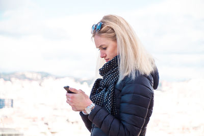 Young woman using mobile phone while standing outdoors