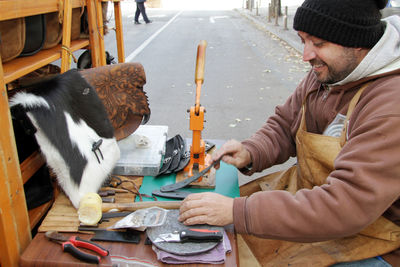 Man working on leather while sitting at table on road