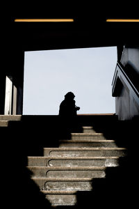 Low angle view of silhouette person standing on staircase against building
