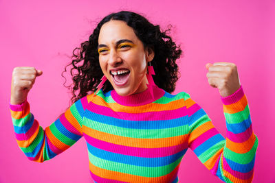 Portrait of smiling young woman standing against yellow background