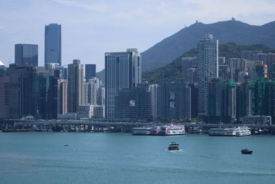 Boats in sea against modern buildings in city