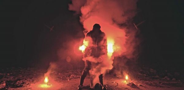 Person wearing gas mask holding smoke bombs