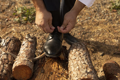 Low section of man tying shoelace on logs