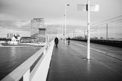 People walking on bridge over rhine river against sky