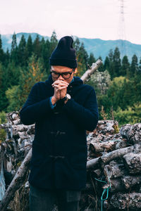 Man standing against logs in forest