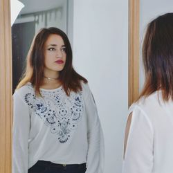 Reflection of woman in mirror standing at home