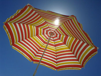 Low angle view of umbrellas against blue sky