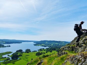 Scenic view of mountains with man on rock against sky