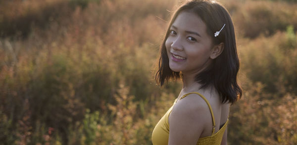 Portrait of smiling young woman standing on field