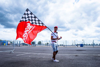 Person standing by flag against sky