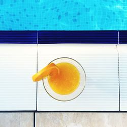 Directly above shot of orange juice glass at poolside
