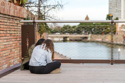 Full length of woman sitting against fence