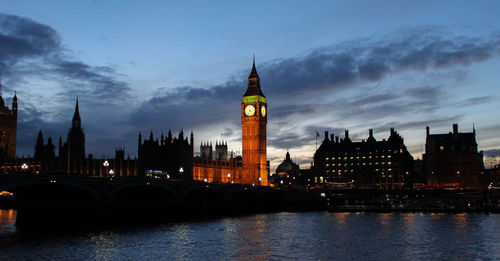 View of illuminated buildings and river against sky