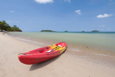 Boat moored on beach against sky