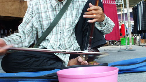 Low section of man playing musical instrument on street