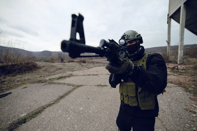 Army soldier aiming while standing against sky