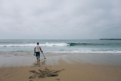 Rear view of friends on beach against sky