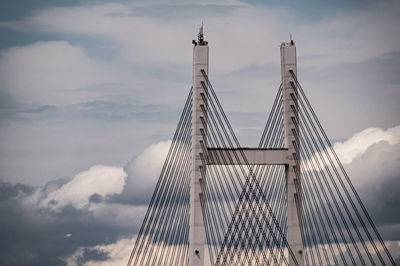 Low angle view of suspension bridge against cloudy sky