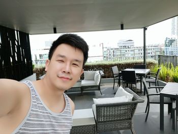 Portrait of man standing by tables and chairs