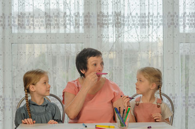 Cute girls sitting with grandmother at home