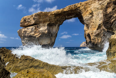 View of rock formation in sea against sky