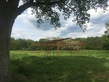 Trees on field against cloudy sky