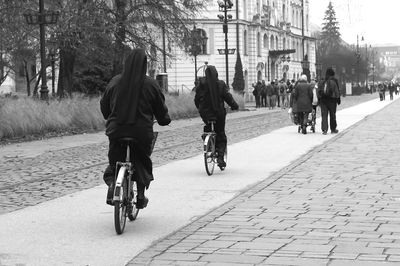 Rear view of people riding bicycle on road
