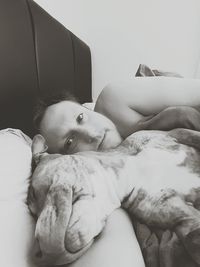 Portrait of shirtless man with his pet dog lying on bed