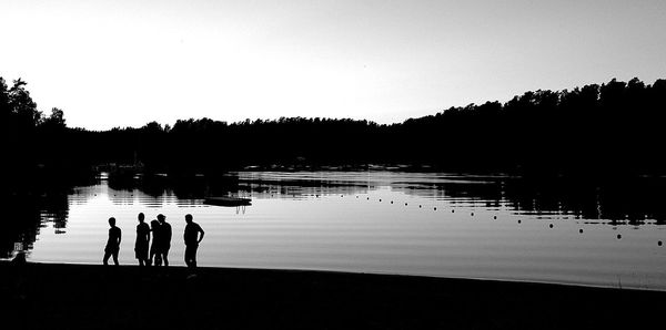 Silhouette trees by lake at sunset