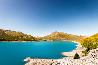 Scenic view of lake and mountains against clear blue sky