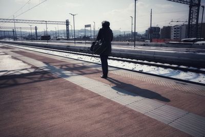 Woman standing on railroad station platform against sky