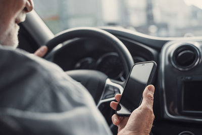 Midsection of man using mobile phone in car