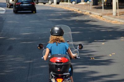 Rear view of people riding motorcycle on road