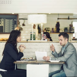 Side view of businessman with female colleague discussing at restaurant table