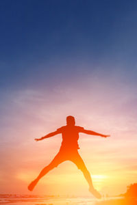 Rear view of silhouette man jumping against sky during sunset