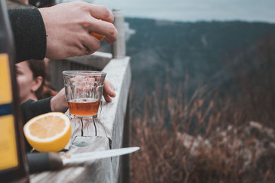 Cropped hand of man squeezing orange fruits in drink