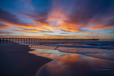 Pier over sea against sky during sunset