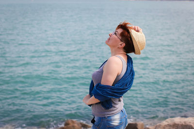 Young woman wearing hat standing at beach